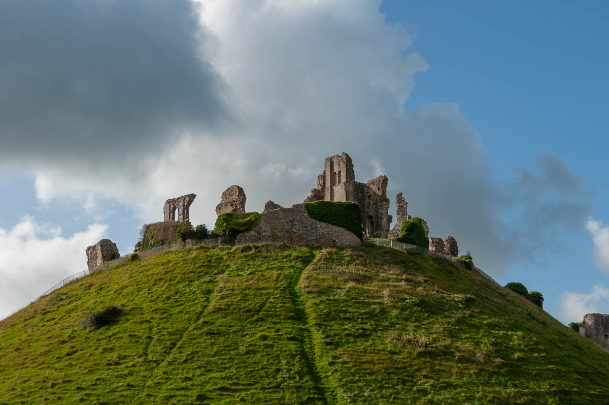 a dramatic view of corfe castle atop hill with darken clouds